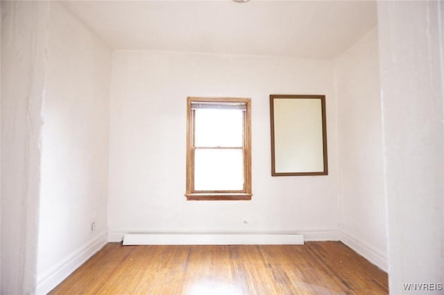 unfurnished room with hardwood / wood-style floors and baseboard heating