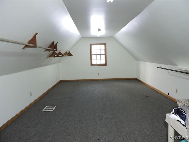 bonus room featuring vaulted ceiling and dark colored carpet