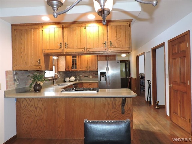 kitchen with backsplash, sink, kitchen peninsula, wood-type flooring, and stainless steel appliances