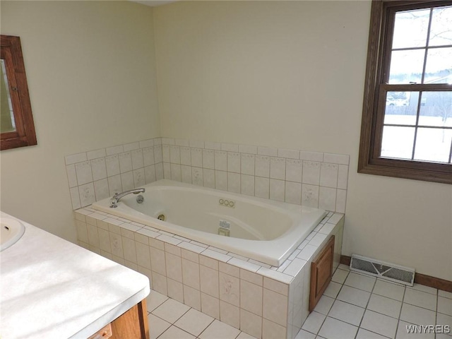 bathroom featuring tile patterned flooring, vanity, and tiled bath