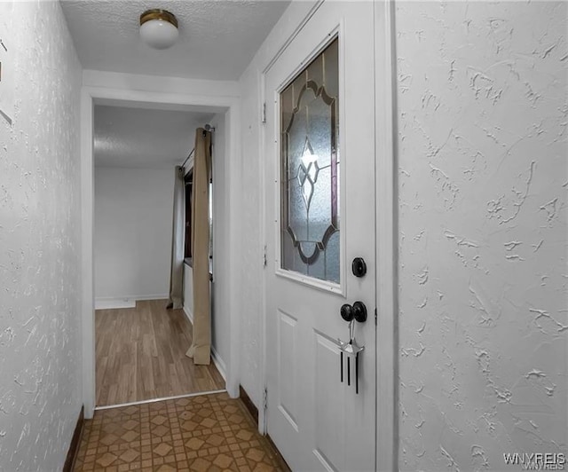 doorway with tile patterned flooring and a textured ceiling