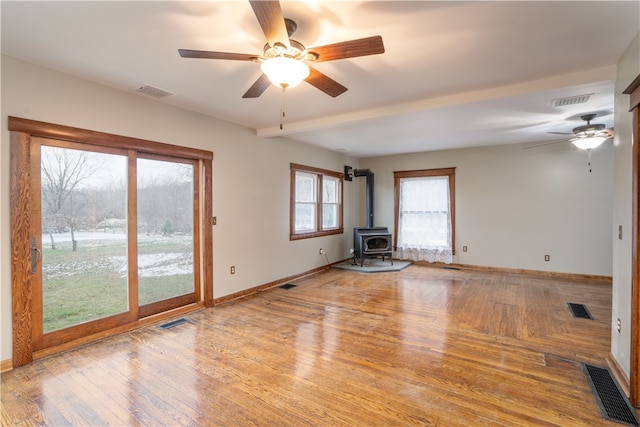 unfurnished living room with a wood stove, ceiling fan, and light hardwood / wood-style flooring