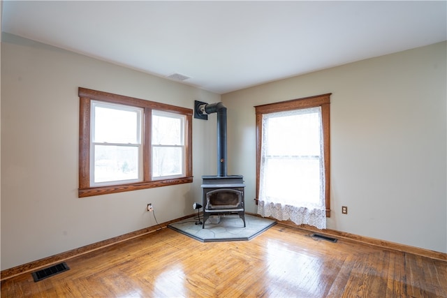 unfurnished living room featuring a wood stove and parquet flooring