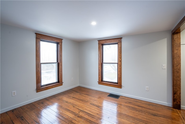 empty room with a wealth of natural light and dark wood-type flooring