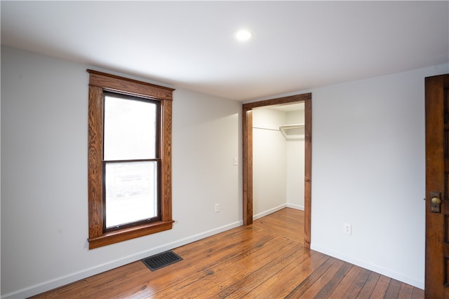 unfurnished bedroom featuring a spacious closet, wood-type flooring, and a closet