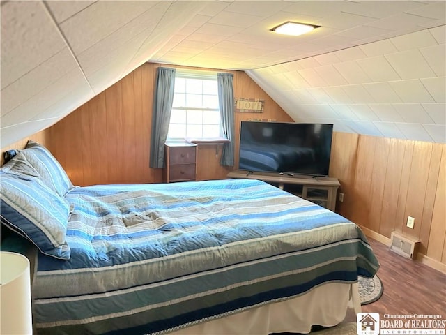 bedroom with hardwood / wood-style flooring, wooden walls, and vaulted ceiling