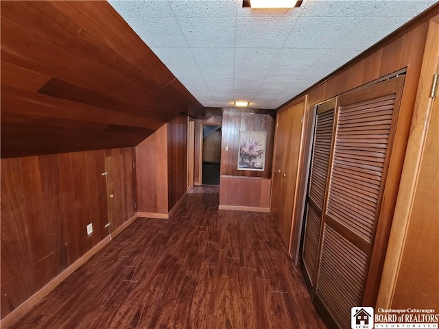 hallway with dark hardwood / wood-style floors and wooden walls