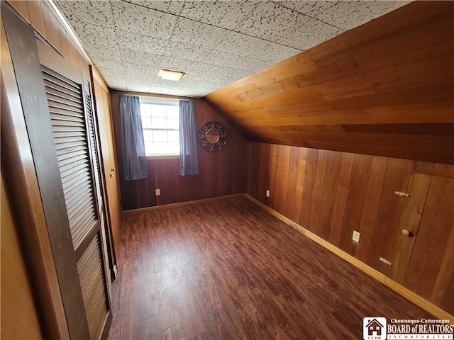 bonus room featuring wood walls, dark hardwood / wood-style flooring, and lofted ceiling