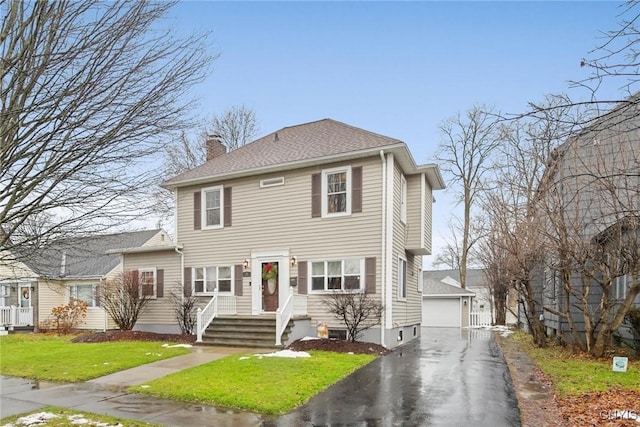 view of front facade featuring an outbuilding, a garage, and a front yard