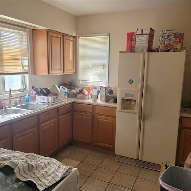 kitchen featuring light tile patterned floors, white fridge with ice dispenser, and sink