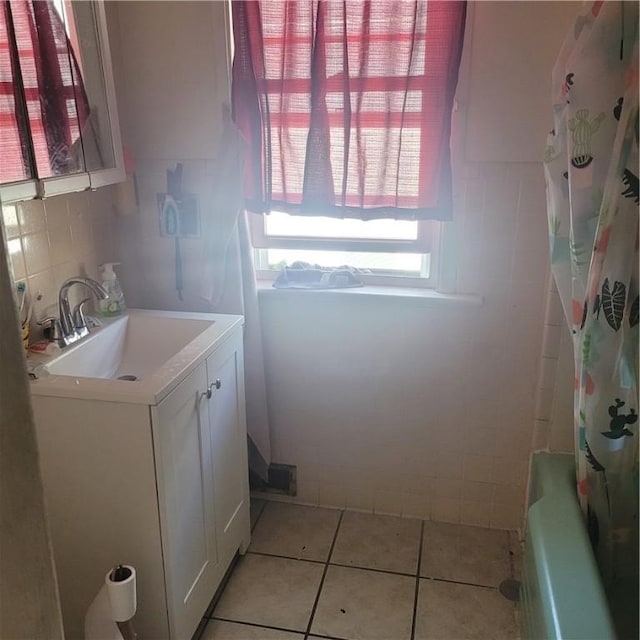 clothes washing area featuring light tile patterned floors, tile walls, and sink