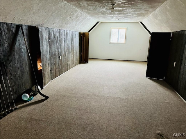 additional living space featuring wooden walls, light colored carpet, and vaulted ceiling