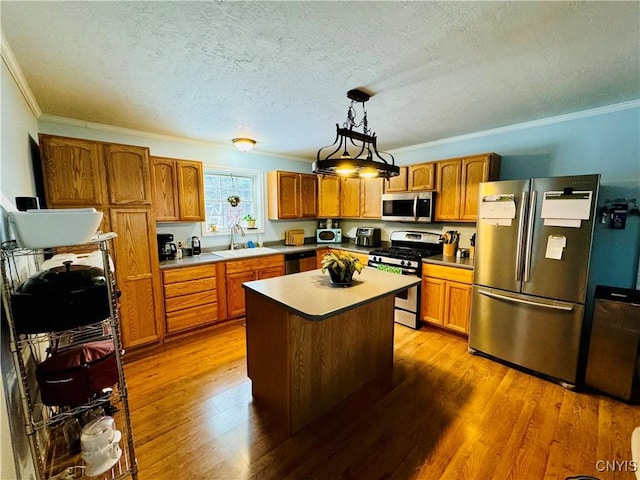 kitchen with pendant lighting, hardwood / wood-style floors, a center island, crown molding, and appliances with stainless steel finishes