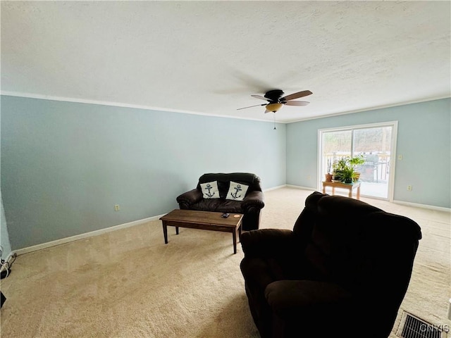 living area with light carpet, ceiling fan, a textured ceiling, and ornamental molding