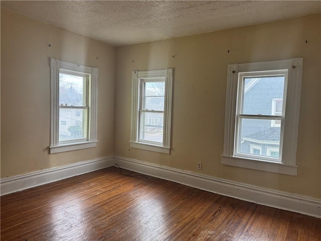 spare room featuring a textured ceiling and dark hardwood / wood-style flooring