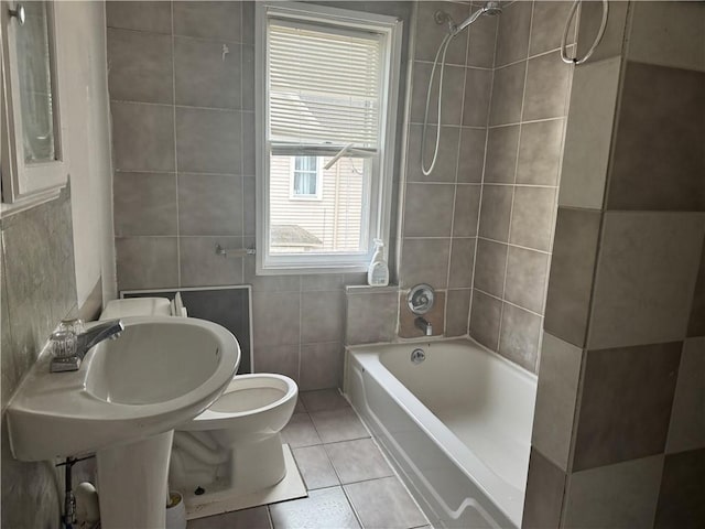 bathroom featuring tile patterned flooring, tiled shower / bath, tile walls, and toilet