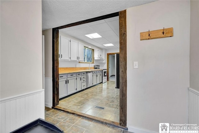 kitchen with white cabinets, stainless steel appliances, and a textured ceiling