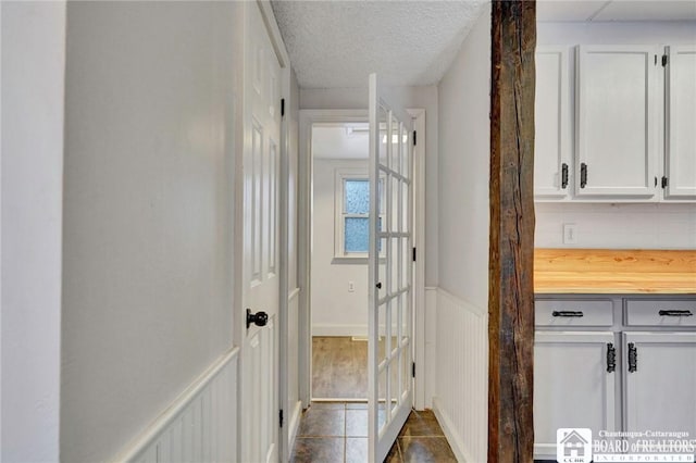 hallway with tile patterned floors and a textured ceiling