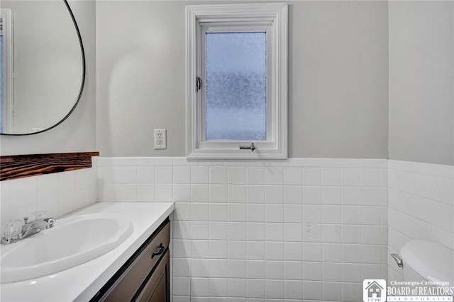 bathroom featuring vanity, toilet, and tile walls