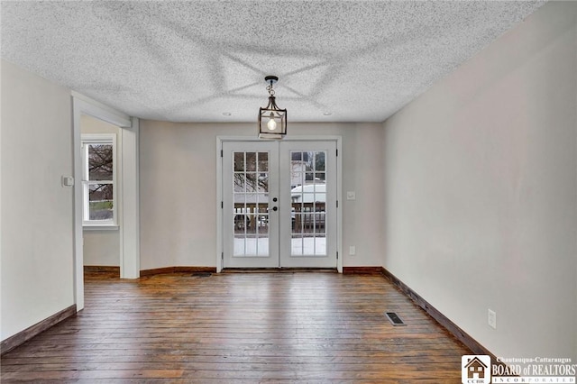 unfurnished dining area featuring french doors, dark wood-type flooring, and a textured ceiling