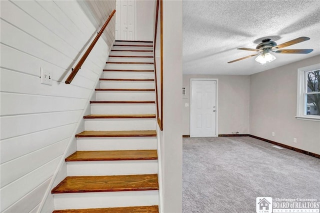 stairs featuring carpet flooring, ceiling fan, and a textured ceiling