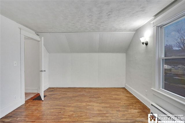 bonus room with a textured ceiling, lofted ceiling, wood-type flooring, and baseboard heating