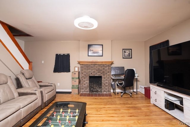 living room with a brick fireplace and light wood-type flooring