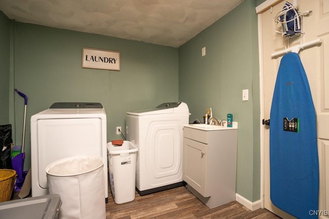 bathroom with hardwood / wood-style flooring, independent washer and dryer, and sink