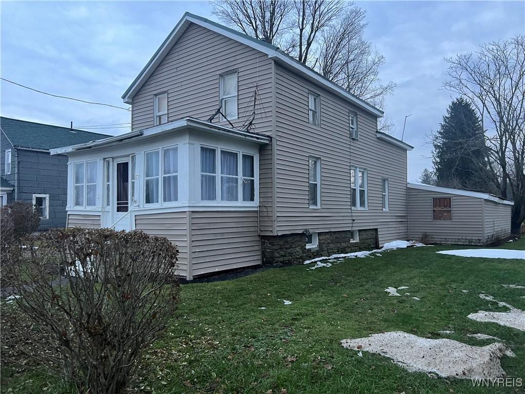 view of property exterior featuring a lawn and a sunroom