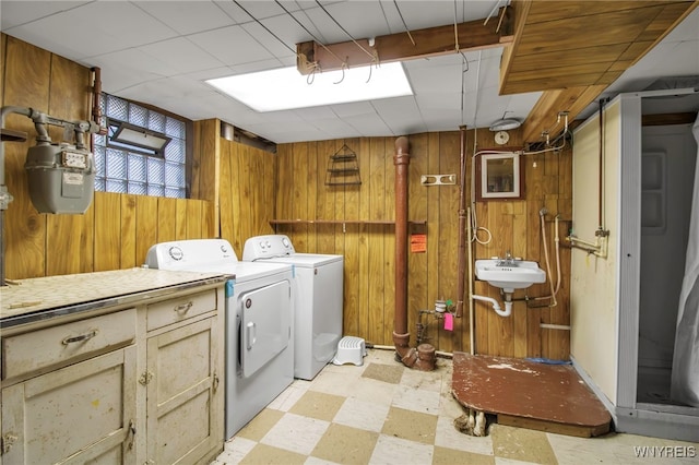 washroom featuring wood walls, independent washer and dryer, and sink