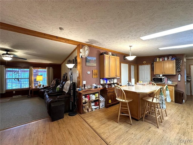 kitchen featuring a textured ceiling, vaulted ceiling with beams, decorative light fixtures, and light hardwood / wood-style flooring