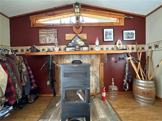 interior space featuring wood-type flooring, vaulted ceiling, and ornamental molding