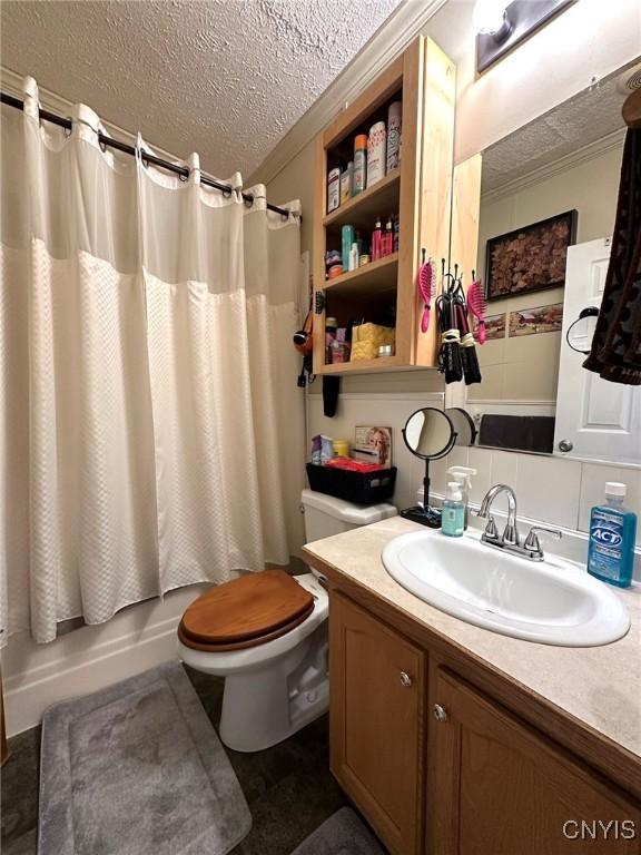 full bathroom featuring vanity, shower / bath combination with curtain, a textured ceiling, and toilet