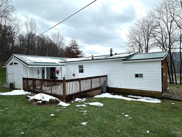 snow covered rear of property with a yard and a deck