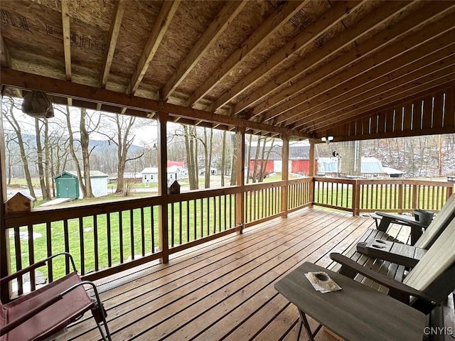 wooden terrace featuring a lawn and a storage unit