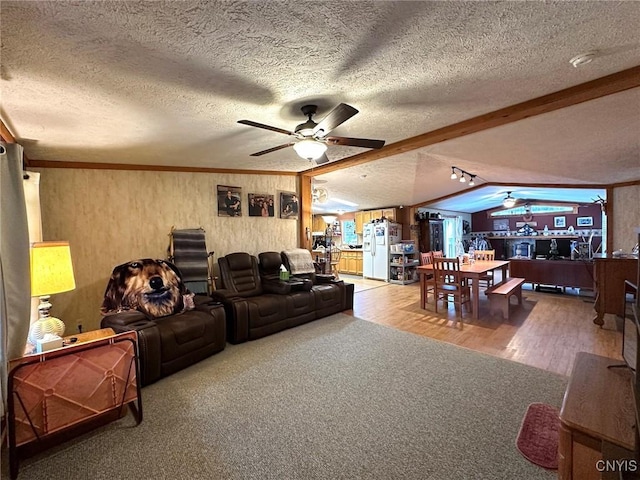 living room featuring vaulted ceiling with beams, a textured ceiling, ceiling fan, and wood-type flooring