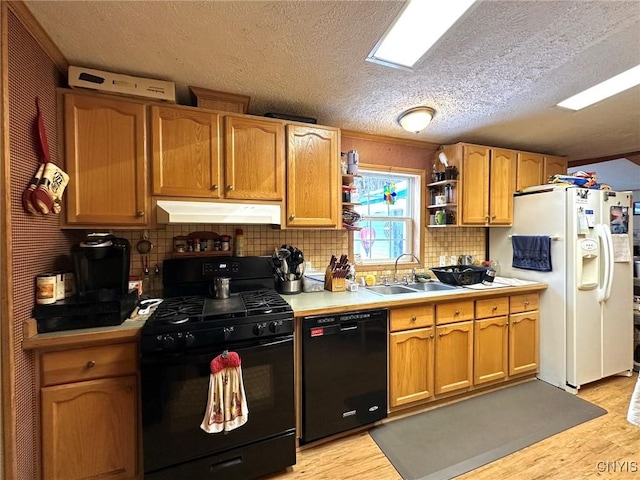 kitchen with black appliances, sink, light hardwood / wood-style flooring, decorative backsplash, and a textured ceiling