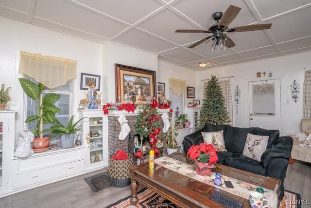 living room featuring wood-type flooring, a brick fireplace, and ceiling fan