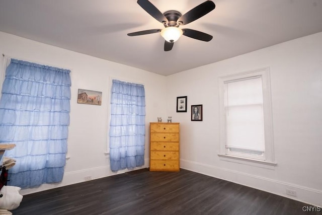 unfurnished bedroom with ceiling fan and dark wood-type flooring