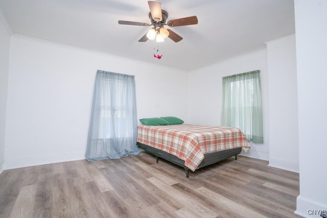 bedroom with ceiling fan, crown molding, and light wood-type flooring