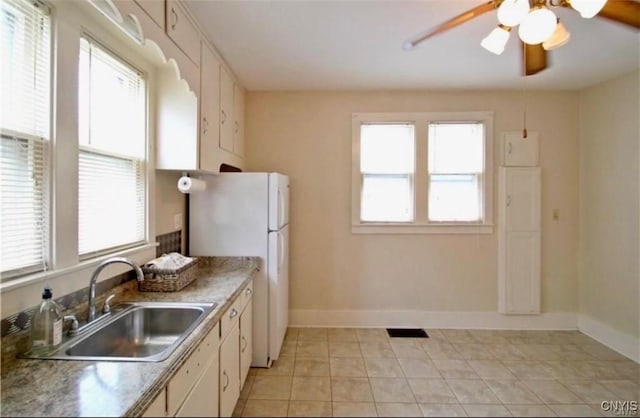 kitchen with light tile patterned floors, white fridge, a wealth of natural light, and sink