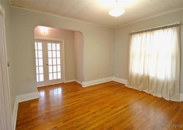 unfurnished room featuring wood-type flooring, crown molding, and french doors