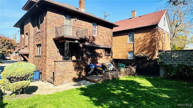 back of property with a yard and a balcony