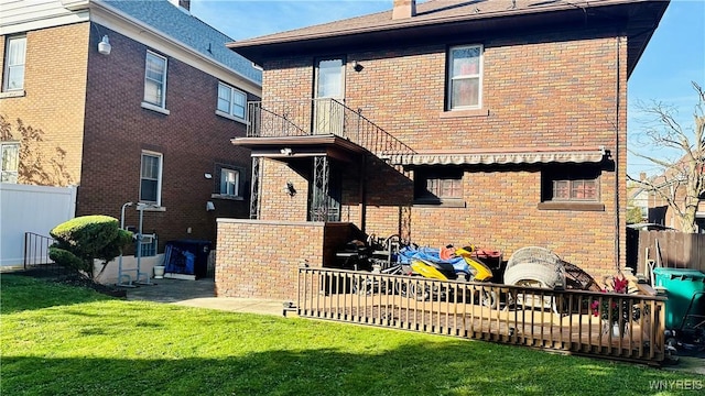 rear view of property featuring a yard and a balcony