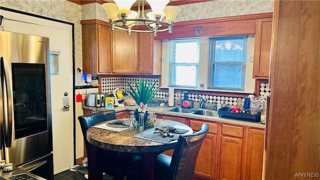 kitchen featuring stainless steel fridge, dark tile patterned floors, sink, a notable chandelier, and hanging light fixtures