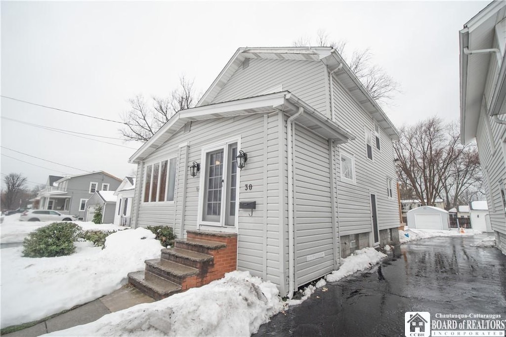 snow covered property with an outdoor structure and a garage