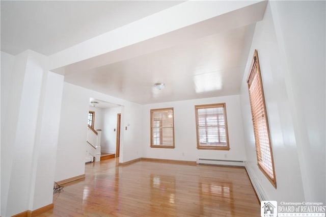 empty room with light hardwood / wood-style floors and baseboard heating