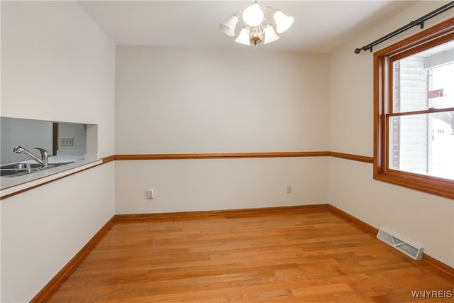 unfurnished dining area with a notable chandelier, light wood-type flooring, and sink