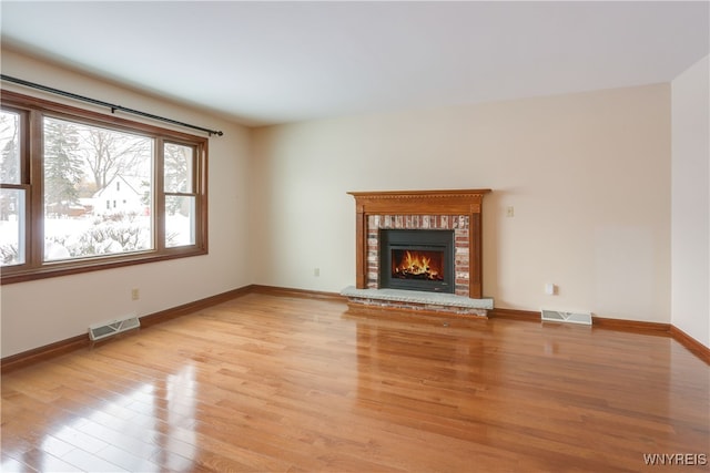 unfurnished living room with light hardwood / wood-style floors and a brick fireplace