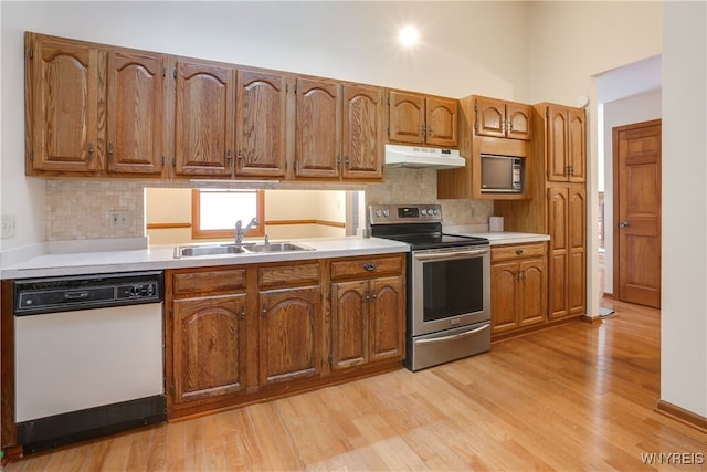 kitchen with backsplash, sink, appliances with stainless steel finishes, and light hardwood / wood-style flooring